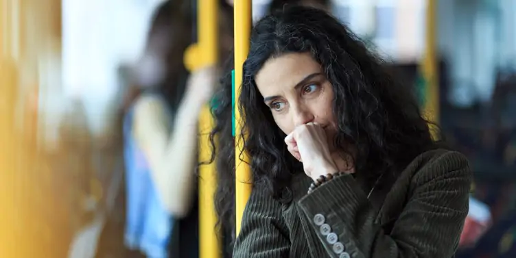 Pensive young woman travelling by bus and holding a smartphone.