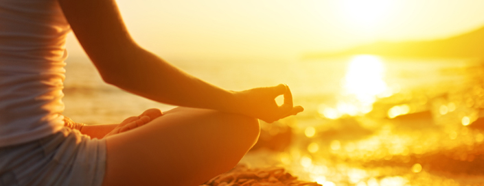 Woman meditating on beach at sunrise