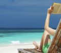 A relaxed woman reading a book in a deckchair on the beach