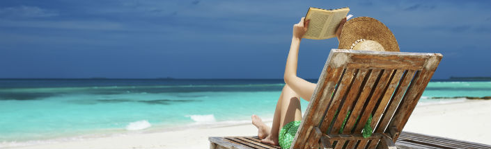 A relaxed woman reading a book in a deckchair on the beach