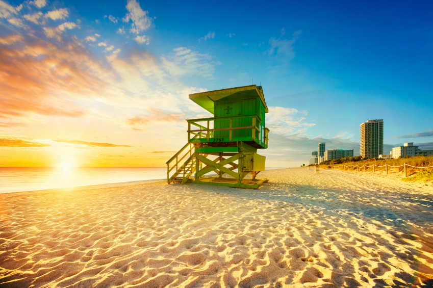 Miami South Beach sunrise with lifeguard tower and coastline with colorful cloud and blue sky.