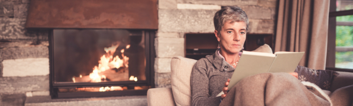 Mature woman keeping warm while reading a book