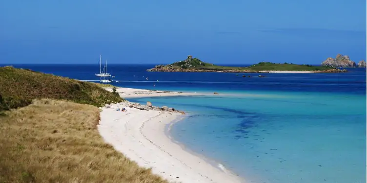 an image of a yacht and the white-sandy beach in Tresco, Isles of Scilly