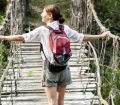 Solo woman traveller crosses a rope bridge