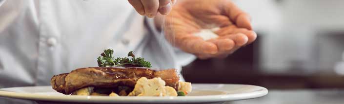 Chef putting salt on meat