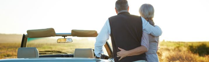 Couple standing by their open top car