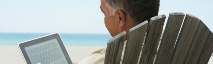 Mature man reading an ebook on the beach