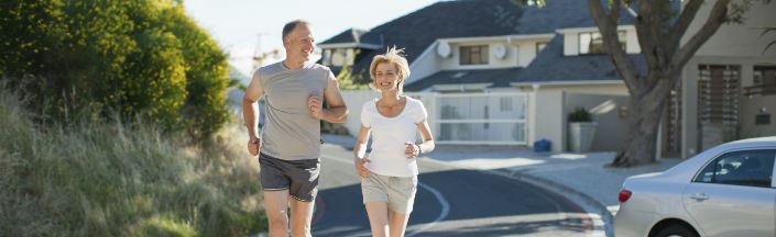 An older couple going on a run on a sunny day