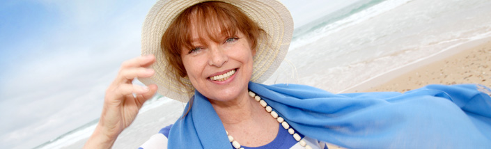 Close up of woman in blue and white, smiling on the beach