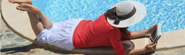 Woman with an ebook reader poolside