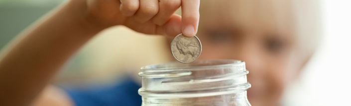 Dropping money into a savings jar