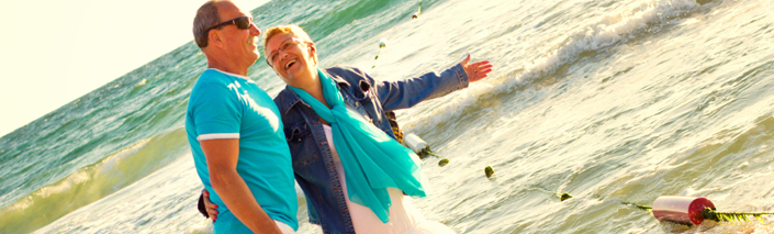 Happy couple, in matching blue, walking along beach together