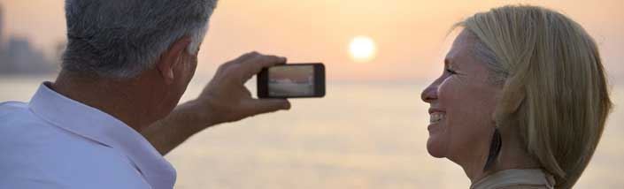 A couple looking at a phone screen in front of a sun setting