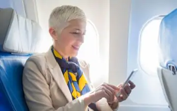 older woman on airplane with phone