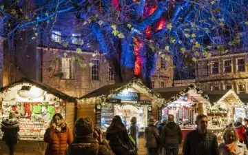 People strolling through the Bath Christmas market in the evening