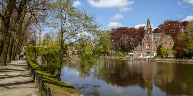 Alt: Tourists going for a walk at the Minnewater lake in Bruges