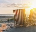 couple on beach in deck chairs at sunset