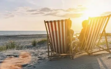 couple on beach in deck chairs at sunset