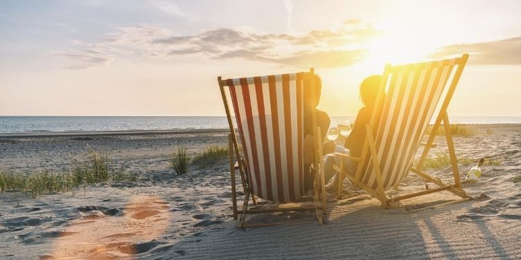 couple on beach in deck chairs at sunset