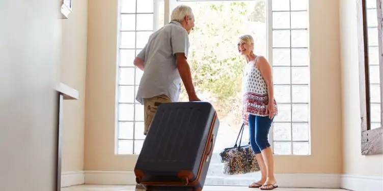 Senior couple leaving for holiday with luggage