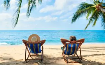 Couple relaxing on deck chairs at the beach