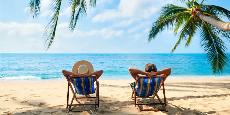 Couple relaxing on deck chairs at the beach
