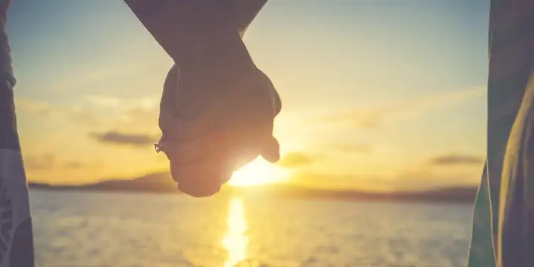 Couple holding hands watching sunset from a cruise ship