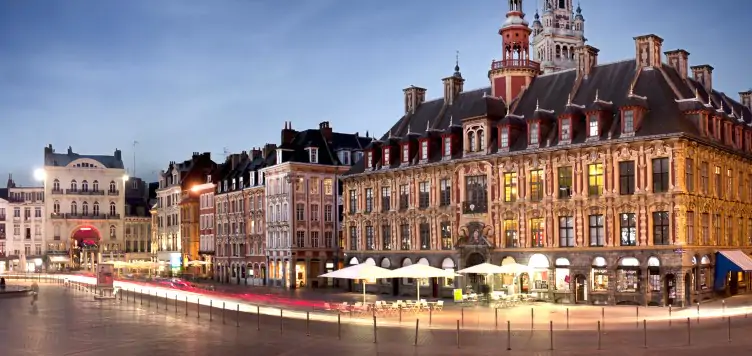  Buildings lit up against the clear nighttime sky in the main square of Lille.