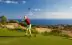 Male golfer teeing off against a background of the ocean