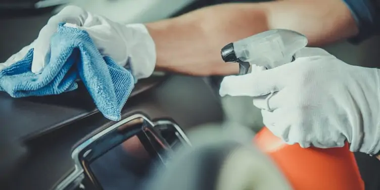 Worker cleaning car dashboard interior