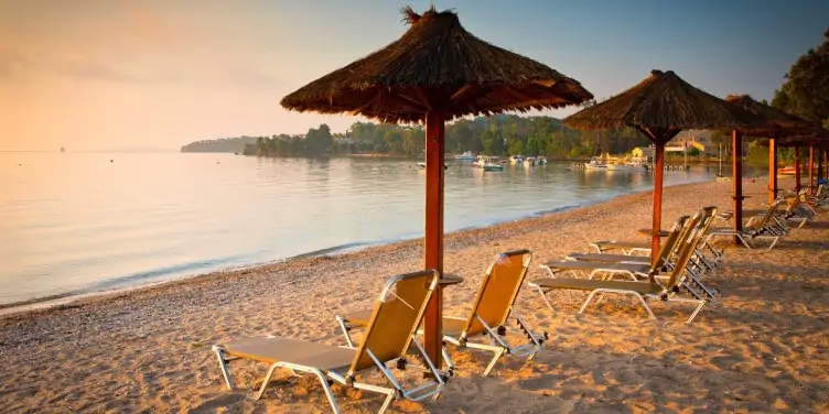 White sand beach with sunbeds and umbrellas in Corfu, Greece