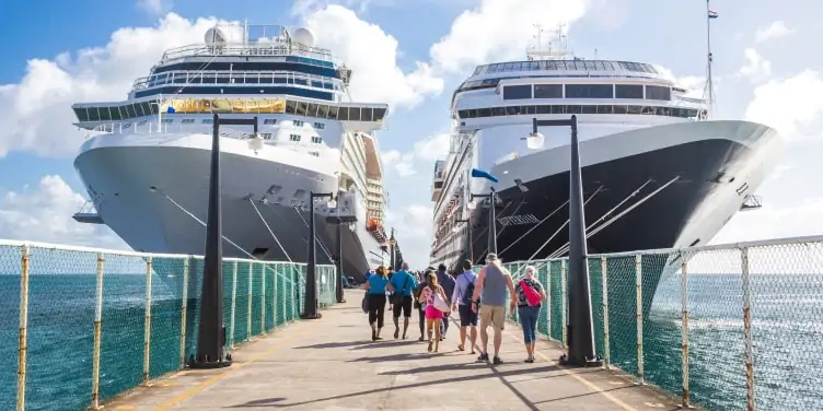 Passengers walk towards two cruise ships to board