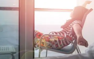 Woman relaxes in chair on the balcony of a cruise ship