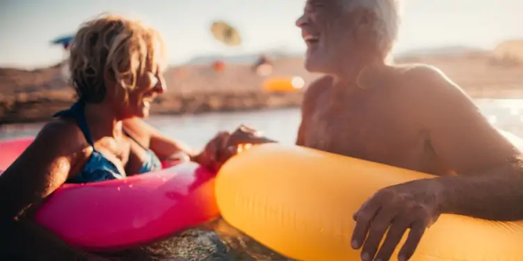 Older couple on holiday having fun in the sea with colourful inflatable rings
