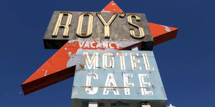  An abandoned Route 66 classic motel sign in Arizona against a cloudy sky.