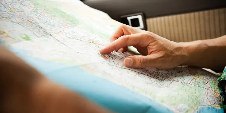  Traveller sitting in a car, holding a roadmap and planning a trip