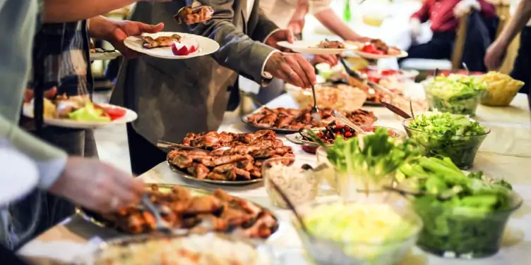 Lots of people help themselves to buffet food laid out on a table