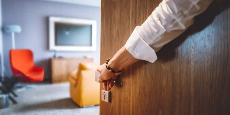 A hotel porter opens a hotel door revealing the room inside