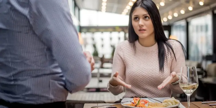 A young woman complains to waiter about her food in a restaurant