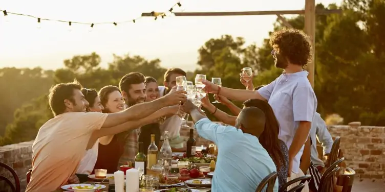 Happy male and female friends toasting wine glasses during summer holiday