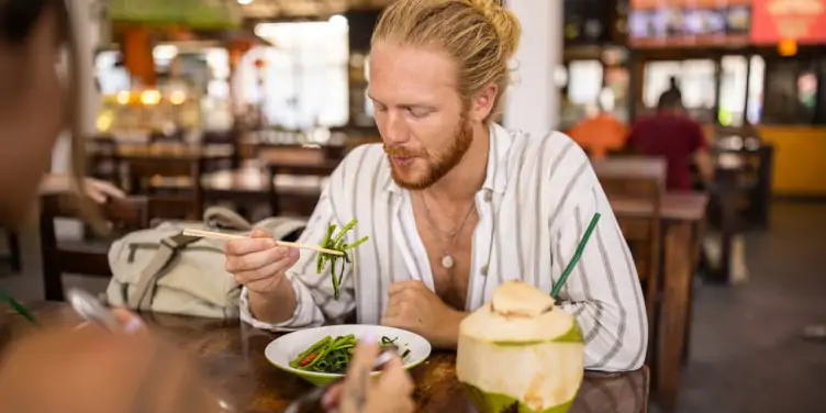 A young man tastes a vegetarian local dish in a Thai restaurant