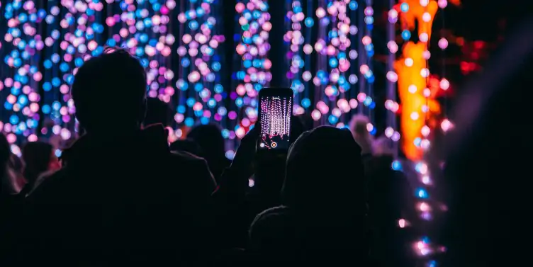 Member of the crowd taking a photo of the hanging lights at Blenhiem Palace Christmas Festival. 