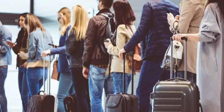 Group of people standing at boarding gate.