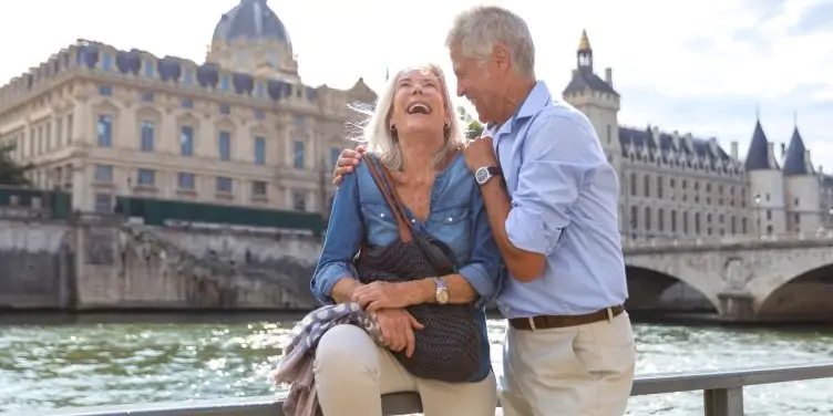 Alt: Seniors on a city break in Paris relaxing on the Seine River 