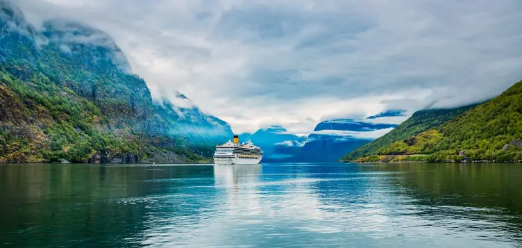 Cruise ship sailing across the open sea, surrounded by a beautiful landscape.