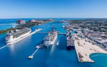 Group of people walking aboard a large cruise ship, ready to set sail.