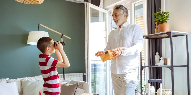 Young boy and his grandfather packing for a trip together, laughing and getting excited for their holiday. 