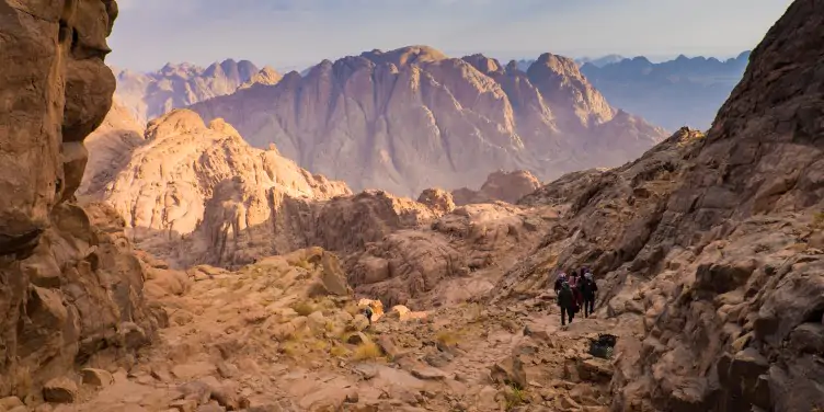 Misty day across the mountain Sinai, with hikers taking on the beautiful walk across the rocks at a distance. 