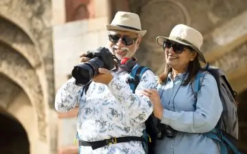 Mature adults looking into camera and laughing at photos on holiday.