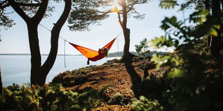 Woman sitting in hammock, looking out across the beautiful big lake. 